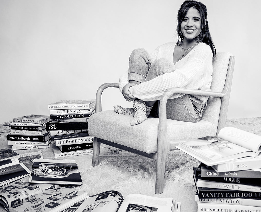 Amber Glassman, CEO and Founder of www.bryananthonys.com sitting on a chair, surrounded by fashion books.