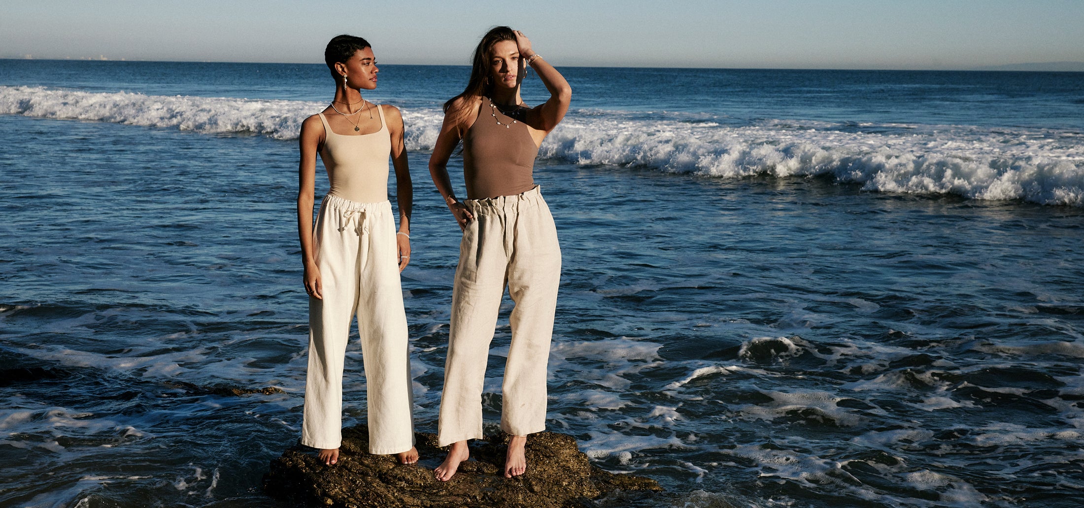 Models on the beach, from afar, wearing grit collection jewelry