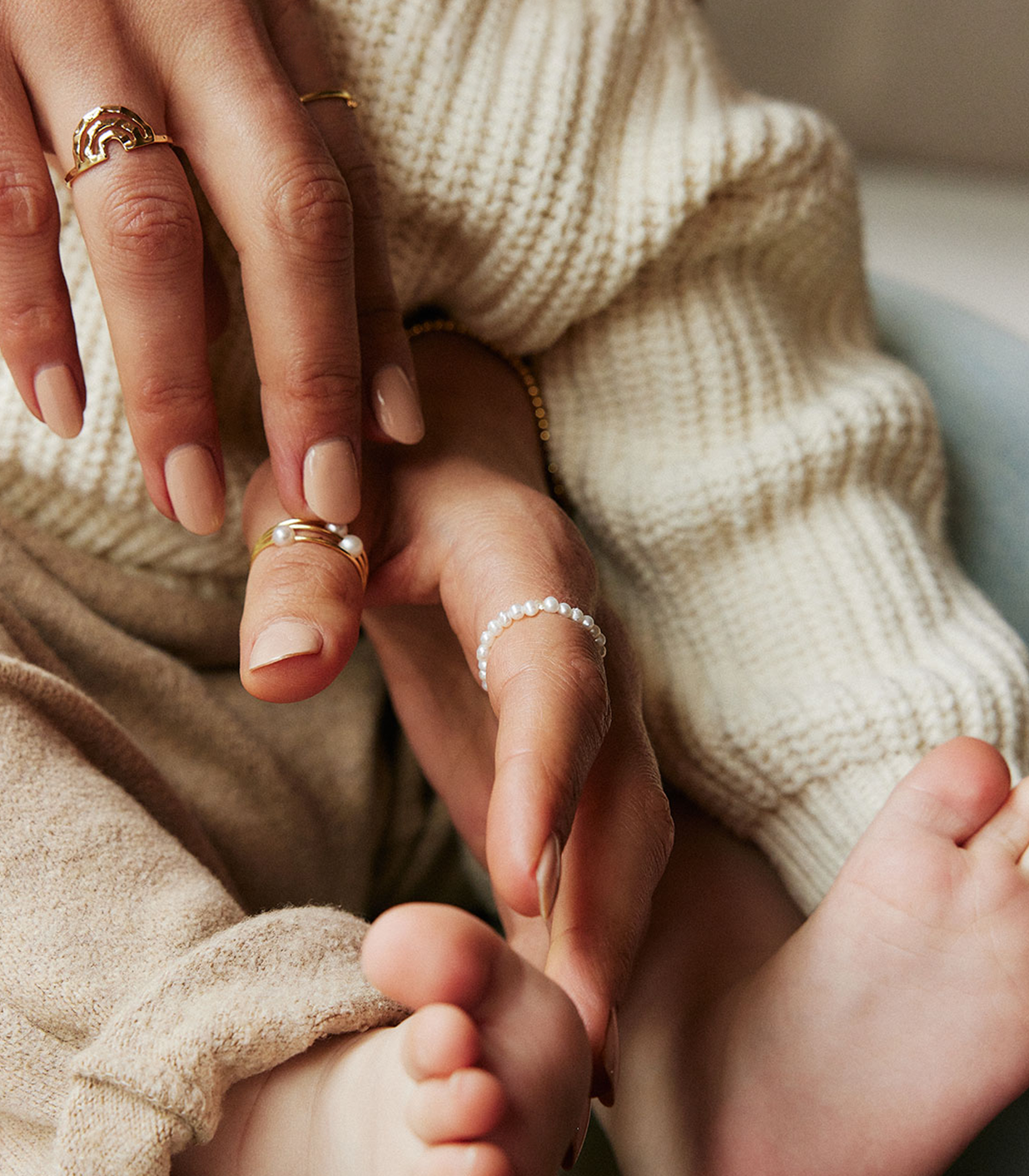 mother and baby daughter holding hands wearing jewelry